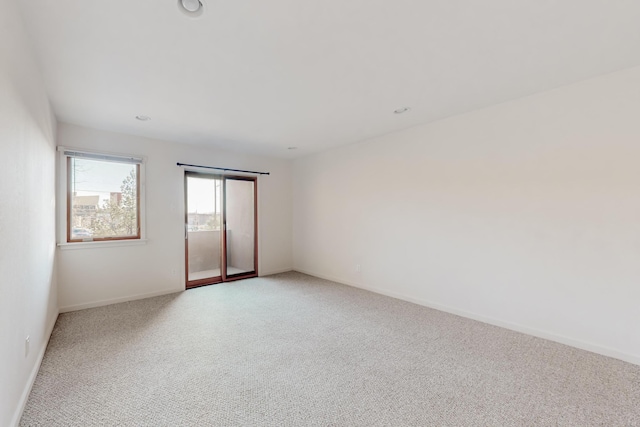 spare room featuring recessed lighting, light colored carpet, and baseboards