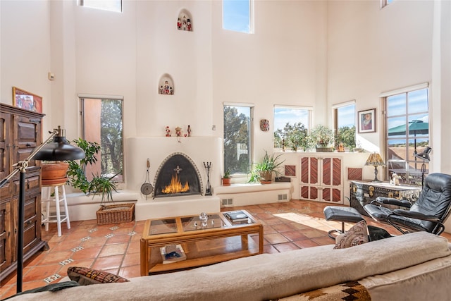 tiled living room with a towering ceiling and a lit fireplace