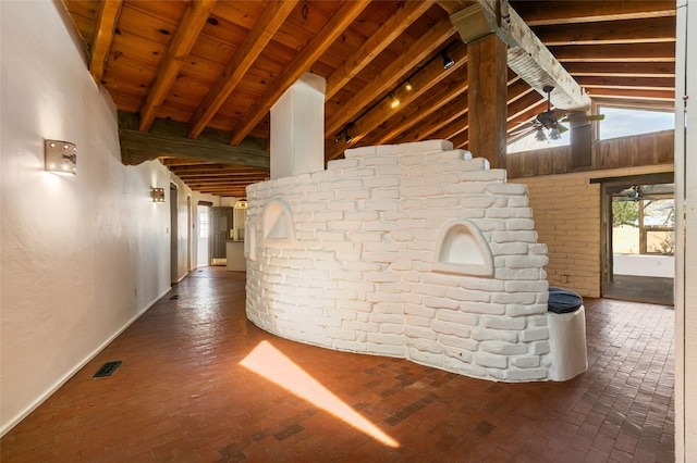 hall with brick floor, wooden ceiling, visible vents, and vaulted ceiling with beams