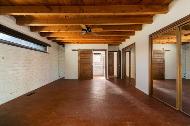 empty room featuring visible vents, a barn door, a ceiling fan, brick wall, and wooden ceiling