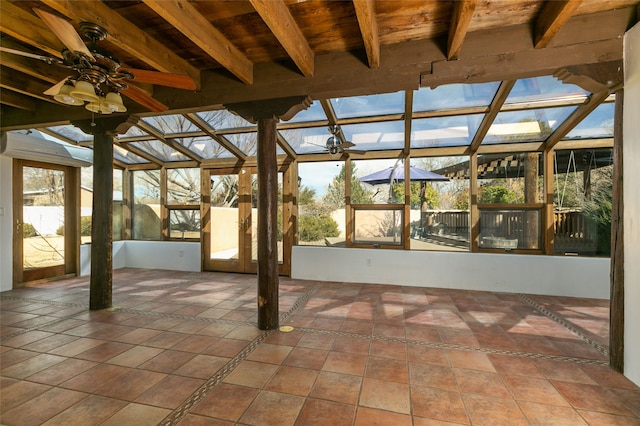 unfurnished sunroom with a ceiling fan and beamed ceiling