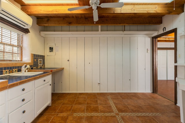 kitchen with tile countertops, a sink, white cabinetry, beamed ceiling, and a wall mounted air conditioner