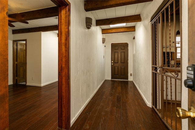 hallway featuring dark wood-style floors, beam ceiling, and baseboards