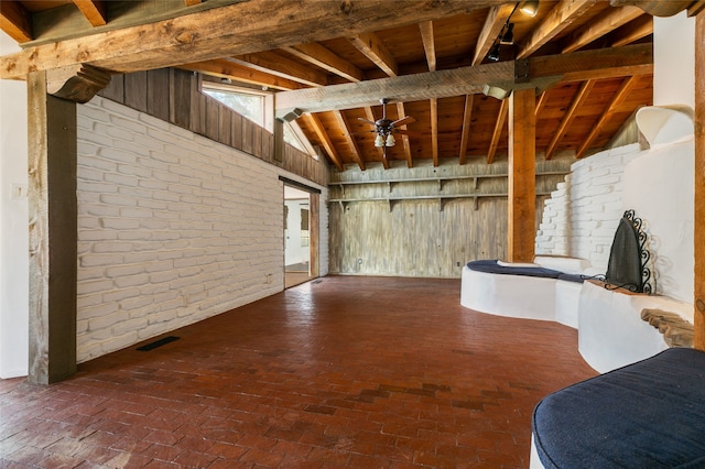 unfurnished living room with vaulted ceiling with beams, brick floor, wooden ceiling, and visible vents