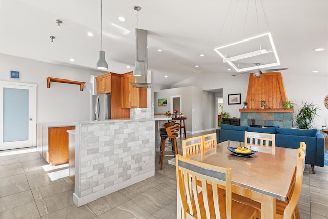 dining space featuring vaulted ceiling, a fireplace, and recessed lighting