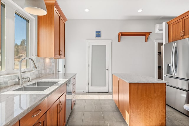 kitchen with appliances with stainless steel finishes, a sink, light stone counters, and a center island