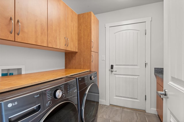 washroom with cabinet space, baseboards, and independent washer and dryer