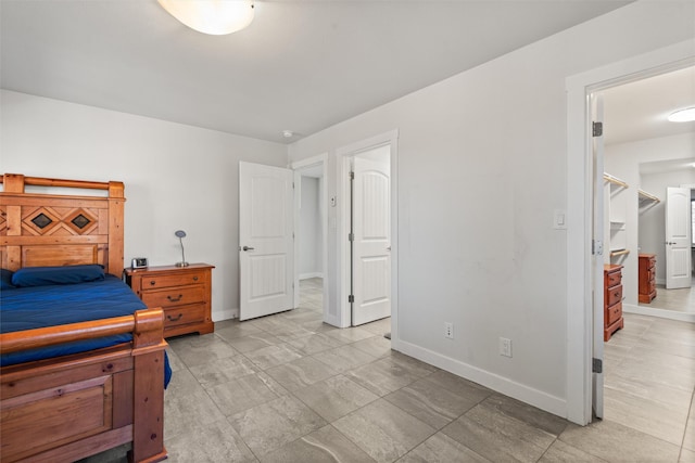 bedroom with baseboards and a walk in closet