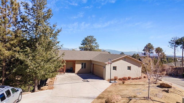 view of front of property featuring driveway, a garage, a mountain view, and stucco siding