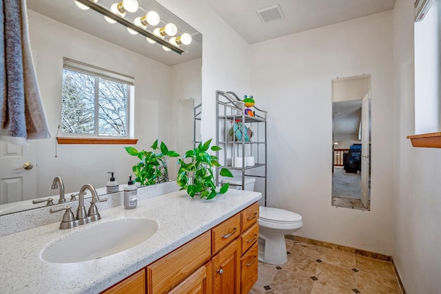 bathroom with baseboards, visible vents, vanity, and toilet