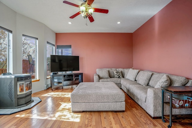 living room featuring ceiling fan, light wood-type flooring, a wood stove, and recessed lighting