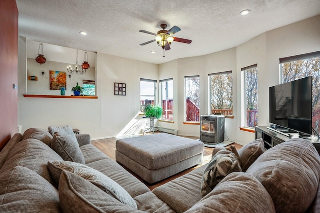 living room featuring recessed lighting, a wood stove, a textured ceiling, and wood finished floors