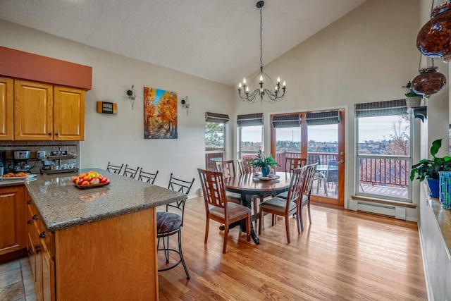 dining area featuring an inviting chandelier, light wood-style flooring, high vaulted ceiling, and baseboard heating