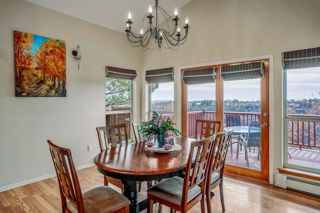 dining space with light wood-style flooring, baseboards, baseboard heating, and a chandelier