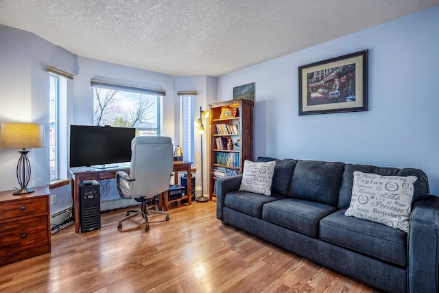 home office with a baseboard heating unit, light wood finished floors, and a textured ceiling