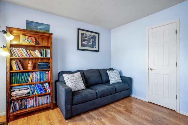 sitting room featuring a textured ceiling, wood finished floors, and baseboards