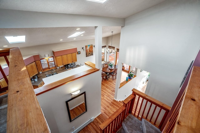 staircase with lofted ceiling, recessed lighting, a textured ceiling, wood finished floors, and a chandelier