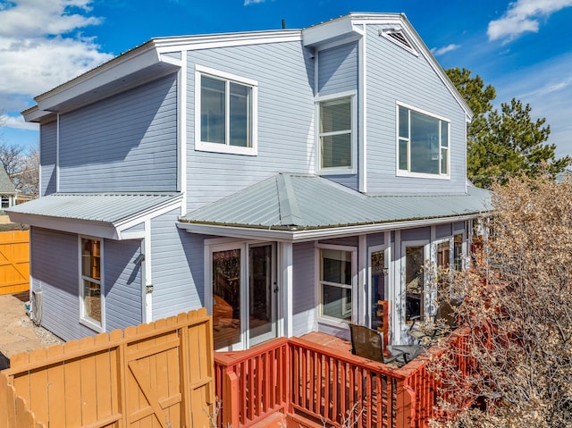 rear view of house with metal roof and fence