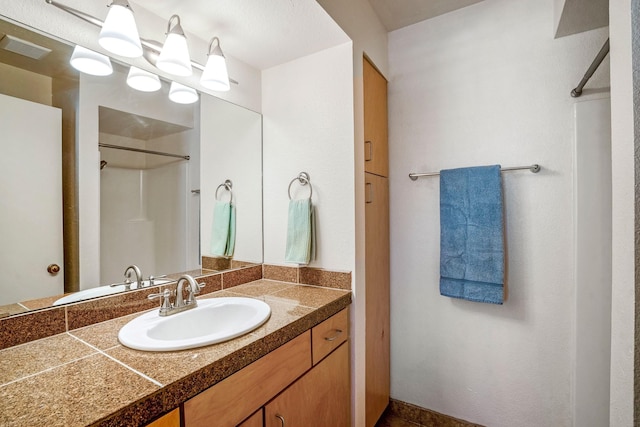 full bath featuring visible vents, walk in shower, and vanity