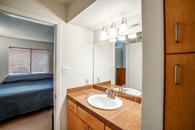 ensuite bathroom with a textured wall, a textured ceiling, ensuite bath, and vanity