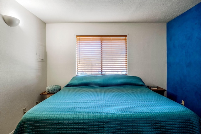 bedroom featuring a textured ceiling and a textured wall