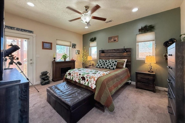 carpeted bedroom featuring a ceiling fan, visible vents, a textured ceiling, and baseboards