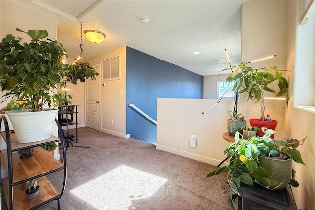 interior space featuring carpet floors, visible vents, a textured ceiling, an upstairs landing, and baseboards