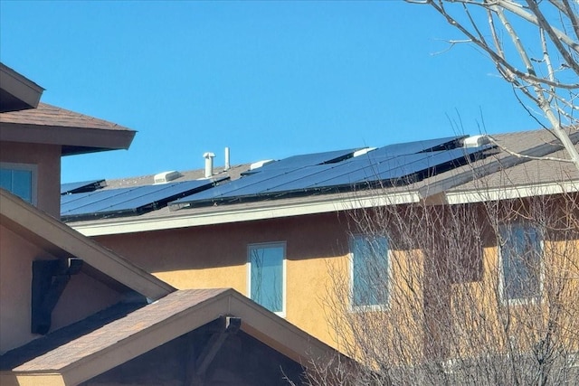 view of home's exterior with solar panels and stucco siding