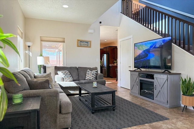 living area featuring a textured ceiling, a high ceiling, and stairway