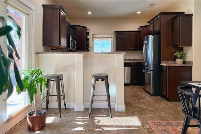 kitchen with stainless steel appliances, recessed lighting, visible vents, dark brown cabinets, and a peninsula