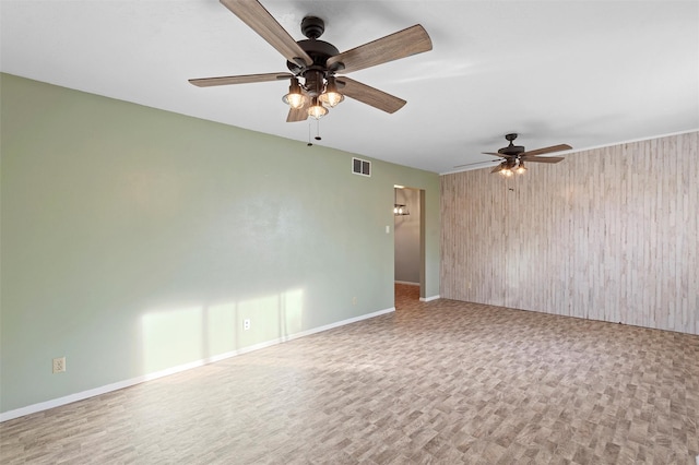 unfurnished room featuring visible vents, wood walls, baseboards, and wood finished floors