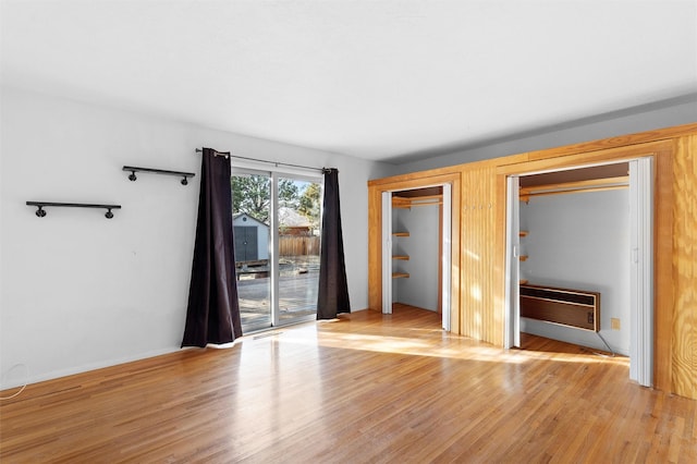 unfurnished bedroom featuring light wood-type flooring, access to exterior, and multiple closets