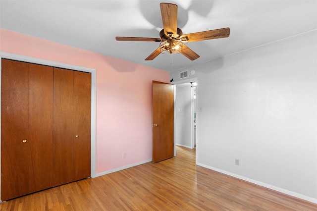 unfurnished bedroom featuring light wood finished floors, a closet, visible vents, a ceiling fan, and baseboards