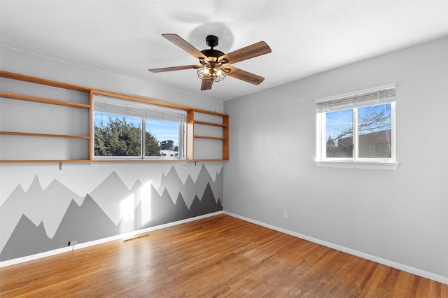 unfurnished room with light wood finished floors, a ceiling fan, visible vents, and baseboards