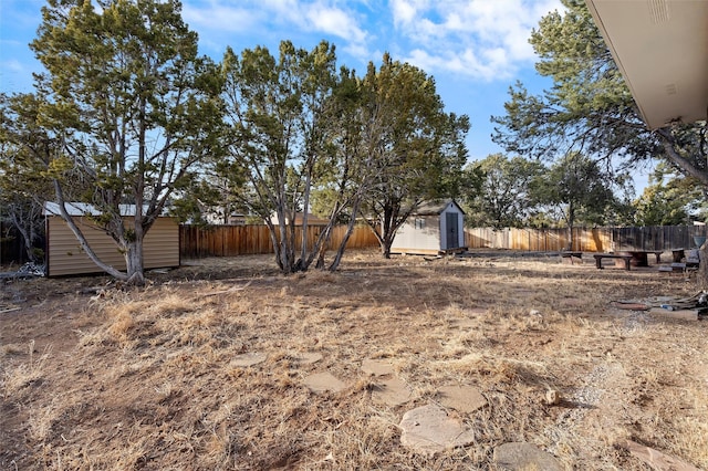 view of yard featuring a fenced backyard, a storage unit, and an outbuilding