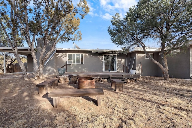 back of property with a deck and stucco siding