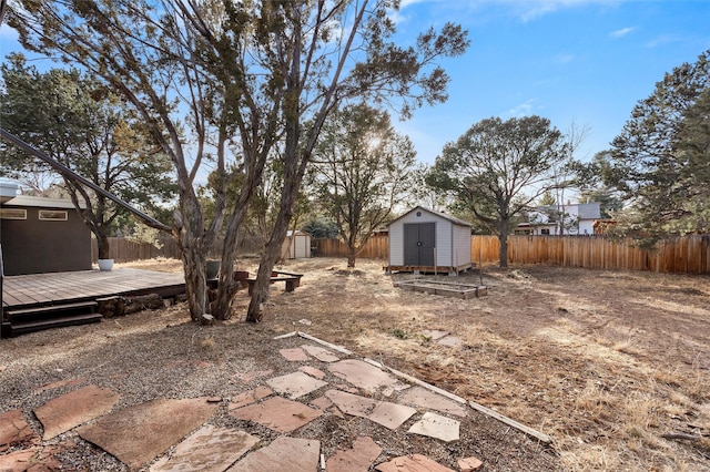 view of yard featuring a deck, a shed, an outdoor structure, and fence