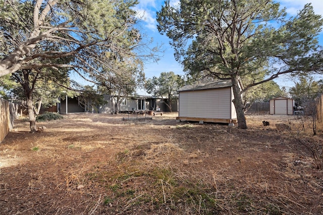 view of yard featuring a shed, fence, and an outbuilding