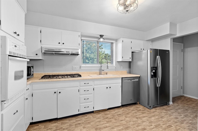 kitchen featuring a sink, stainless steel appliances, light countertops, and under cabinet range hood