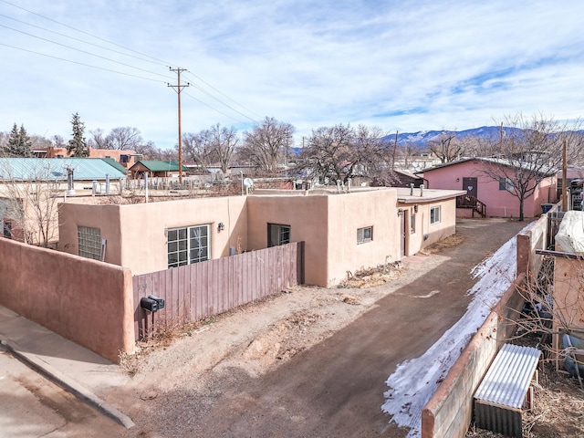 view of property exterior featuring driveway, a fenced front yard, a mountain view, and stucco siding