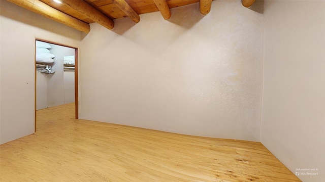 empty room featuring light wood-style floors, wood ceiling, and beamed ceiling