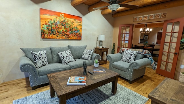 living room with beam ceiling, french doors, wood finished floors, and ceiling fan with notable chandelier