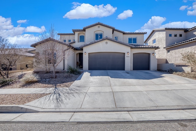 mediterranean / spanish house featuring driveway, a tiled roof, an attached garage, and stucco siding