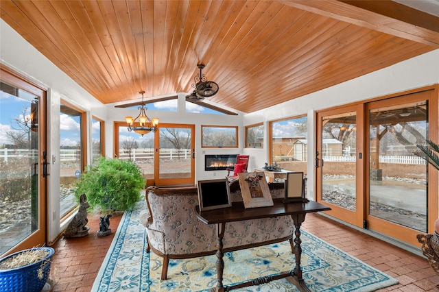 sunroom featuring lofted ceiling, wooden ceiling, a chandelier, and a glass covered fireplace