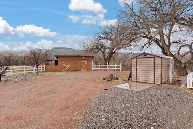 view of yard featuring an outbuilding, fence, and a storage shed