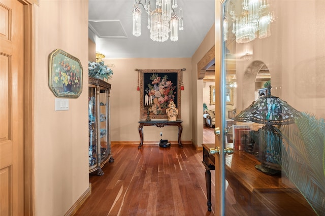 hallway with a chandelier, wood finished floors, and baseboards