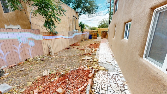 view of side of home featuring a fenced backyard and stucco siding