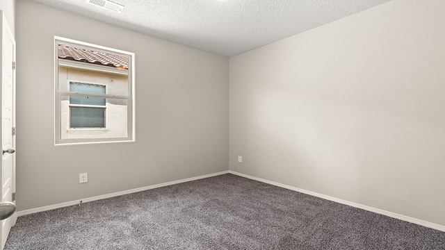 spare room featuring a textured ceiling, carpet floors, visible vents, and baseboards