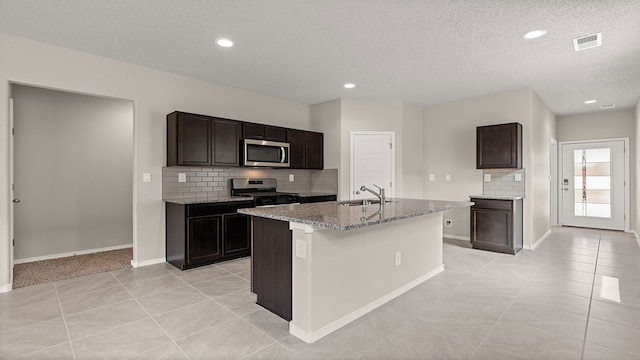 kitchen featuring light tile patterned floors, light stone counters, stainless steel appliances, a sink, and visible vents