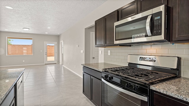 kitchen featuring stone countertops, stainless steel appliances, decorative backsplash, and light tile patterned flooring